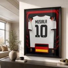 Frameworth - Coupe du Monde FIFA 2026 Officielle Allemagne Jamal Musiala Cadre Réplique de Maillot - 25,75 po x 33,75 po-Encadré professionnellement au Canada, la réplique de maillot est montée dans un cadre noir de qualité supérieure avec façade protectrice transparente.